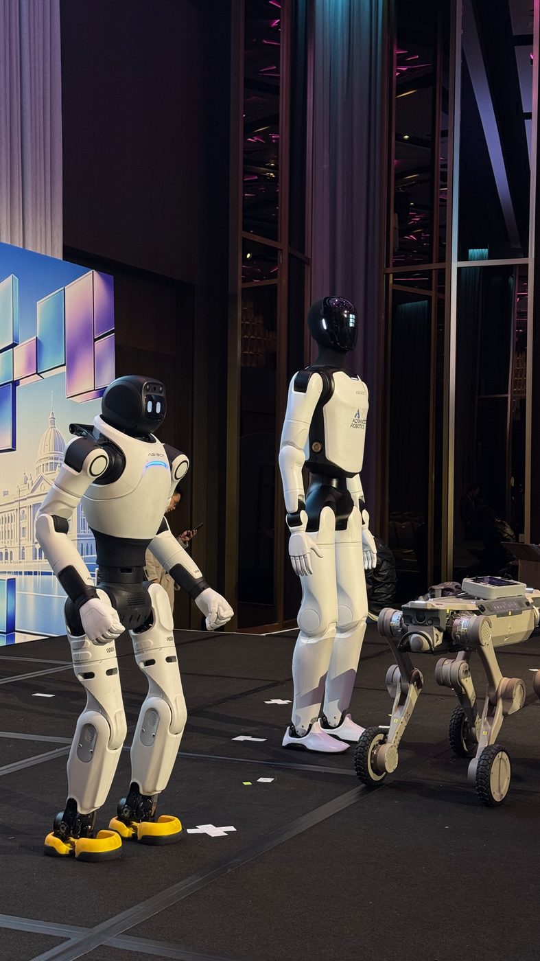 Agibot X2 and Agibot A3 humanoid robots with a quadruped robot standing together on stage